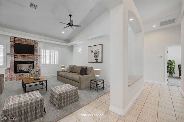 living room featuring a brick fireplace, light tile patterned floors, ceiling fan, and vaulted ceiling