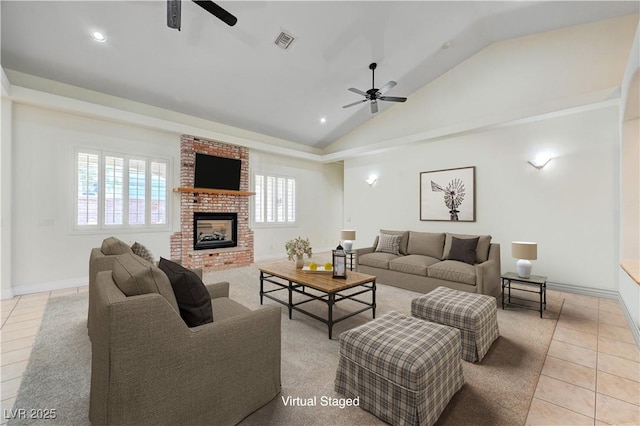 tiled living room with lofted ceiling, ceiling fan, plenty of natural light, and a brick fireplace