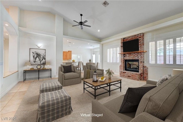 living room with a brick fireplace, plenty of natural light, ceiling fan, and light tile patterned flooring