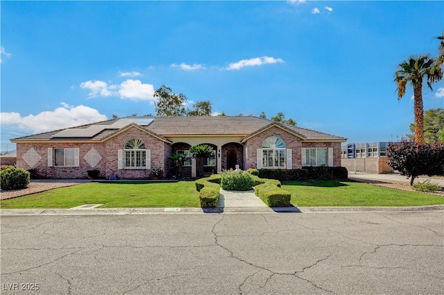 ranch-style home featuring a front yard and solar panels