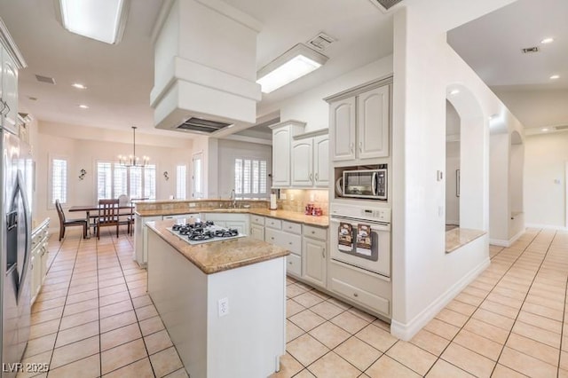 kitchen with sink, kitchen peninsula, light tile patterned flooring, and stainless steel appliances