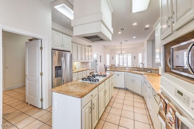 kitchen featuring light tile patterned floors, kitchen peninsula, appliances with stainless steel finishes, decorative light fixtures, and a center island