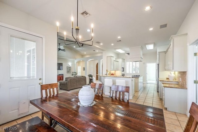 tiled dining space featuring vaulted ceiling and ceiling fan with notable chandelier