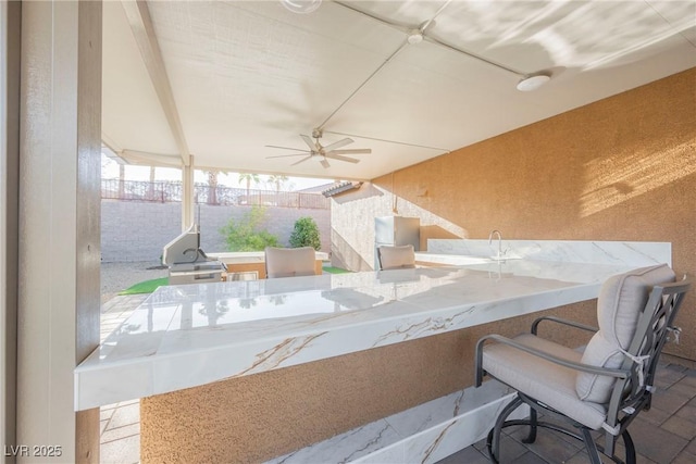 view of patio / terrace featuring a bar, ceiling fan, and exterior kitchen