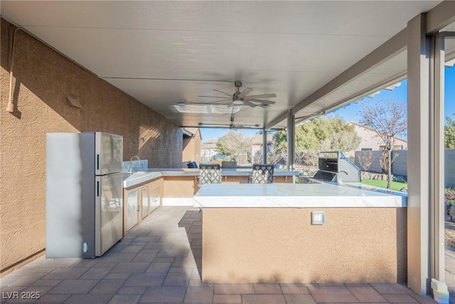 view of patio / terrace featuring exterior kitchen, ceiling fan, and an outdoor wet bar