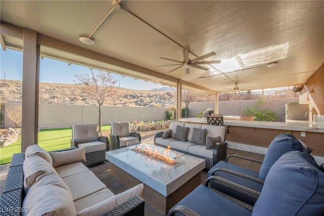 view of patio / terrace with ceiling fan, a mountain view, and an outdoor living space with a fire pit