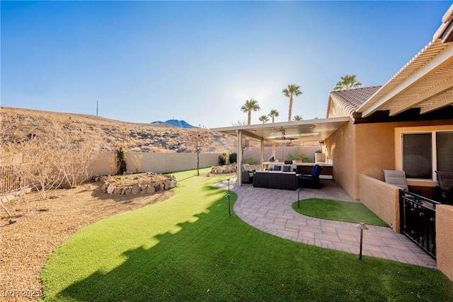 view of yard with a patio area, outdoor lounge area, a mountain view, ceiling fan, and exterior kitchen