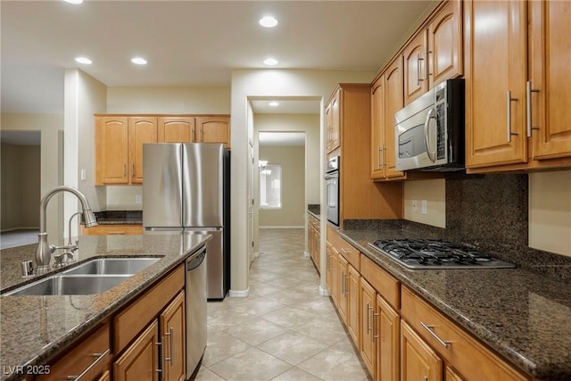 kitchen featuring appliances with stainless steel finishes, sink, backsplash, and dark stone counters