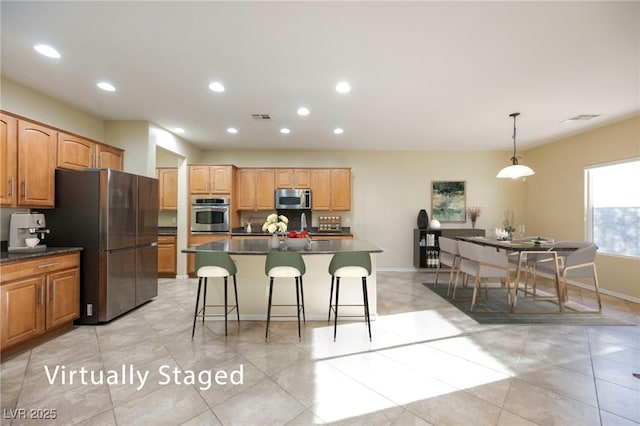 kitchen with appliances with stainless steel finishes, decorative light fixtures, a center island, and a kitchen breakfast bar