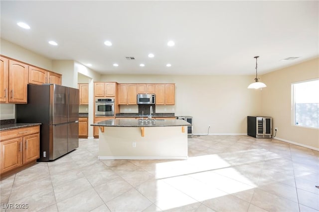 kitchen featuring a kitchen bar, sink, decorative light fixtures, an island with sink, and stainless steel appliances