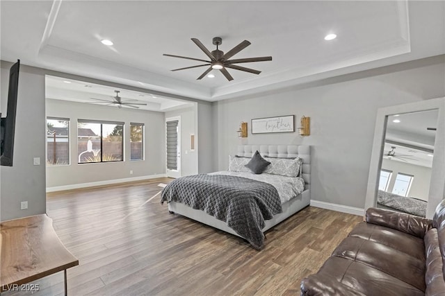 bedroom featuring a raised ceiling, ceiling fan, crown molding, and wood-type flooring