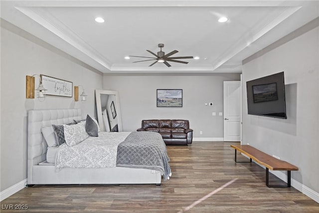 bedroom with ceiling fan, crown molding, hardwood / wood-style flooring, and a tray ceiling