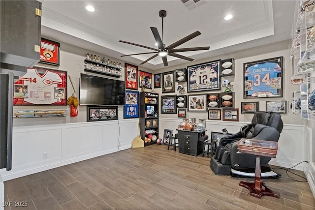 recreation room with ceiling fan, crown molding, and a raised ceiling