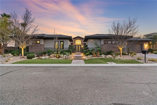 prairie-style home featuring a garage and a yard