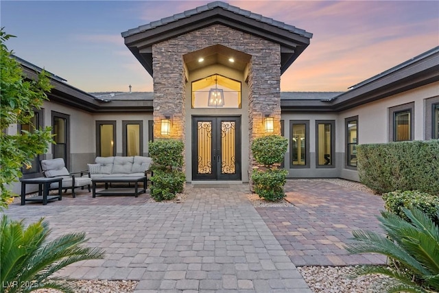 exterior entry at dusk featuring french doors, a patio area, and outdoor lounge area