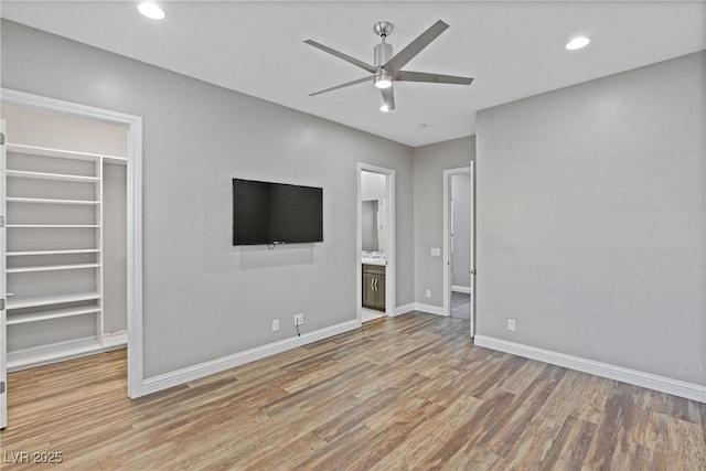 interior space with hardwood / wood-style floors, ensuite bath, a walk in closet, a closet, and ceiling fan