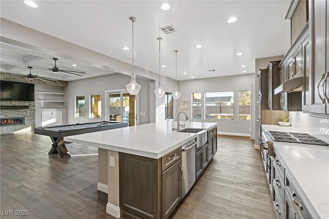 kitchen with dishwasher, decorative light fixtures, a fireplace, billiards, and a kitchen island with sink