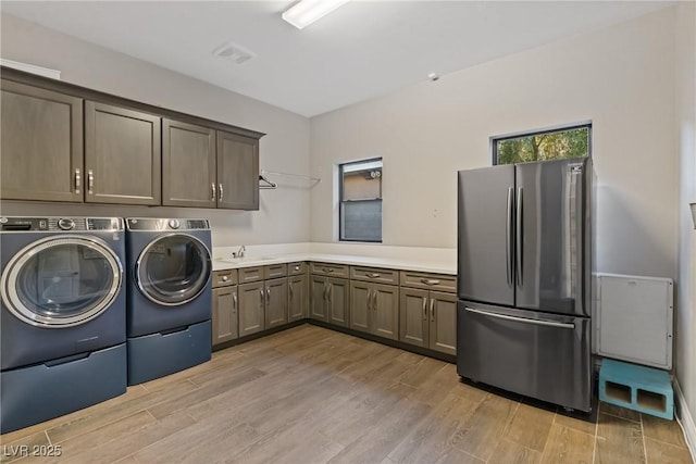 laundry room with cabinets, light hardwood / wood-style floors, independent washer and dryer, and sink