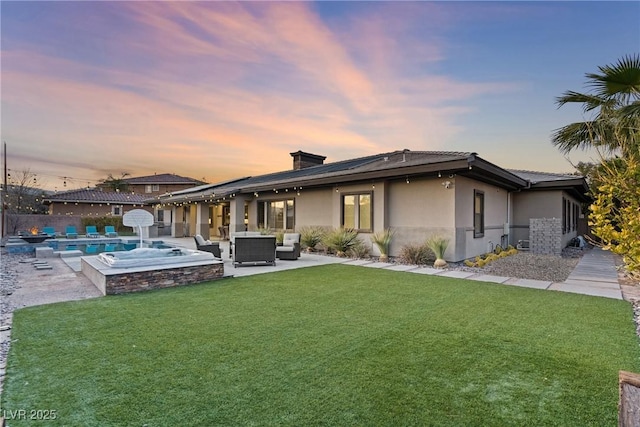 back house at dusk featuring a swimming pool with hot tub, outdoor lounge area, a lawn, and a patio area