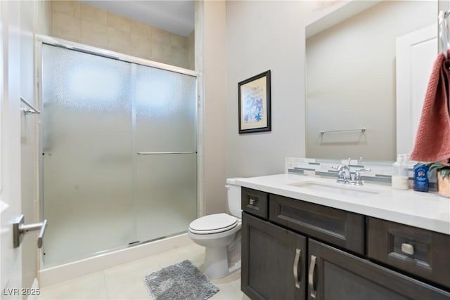 bathroom featuring toilet, vanity, tile patterned floors, and a shower with door