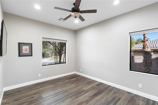 spare room featuring ceiling fan, a wealth of natural light, and dark hardwood / wood-style flooring