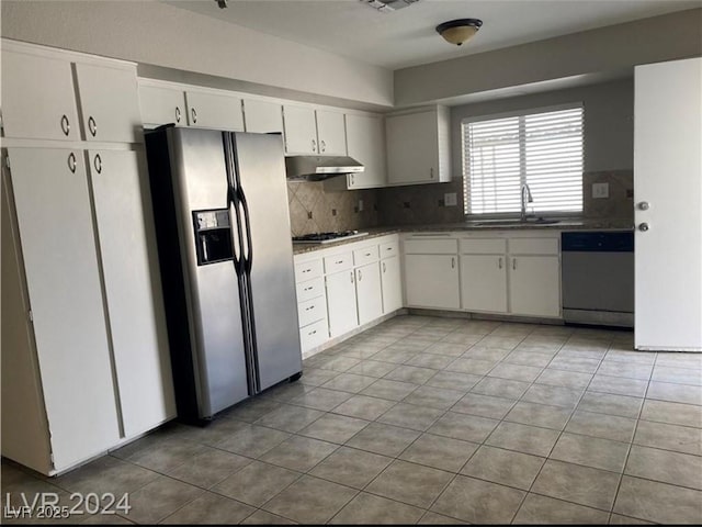 kitchen with tile patterned flooring, white cabinetry, stainless steel appliances, tasteful backsplash, and sink