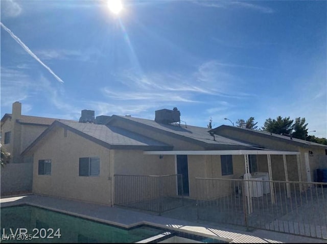 back of property with a fenced in pool and a patio