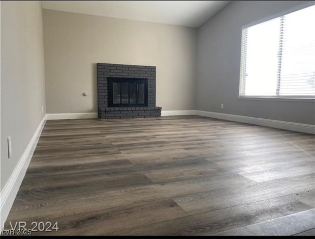 unfurnished living room with vaulted ceiling, dark hardwood / wood-style flooring, and a fireplace