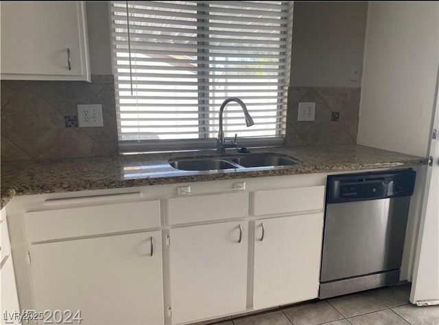 kitchen featuring white cabinetry, light tile patterned flooring, dark stone countertops, stainless steel dishwasher, and sink