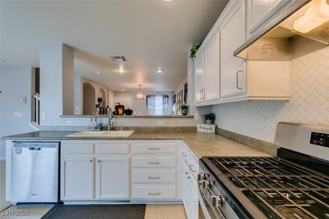 kitchen featuring backsplash, kitchen peninsula, sink, appliances with stainless steel finishes, and white cabinets