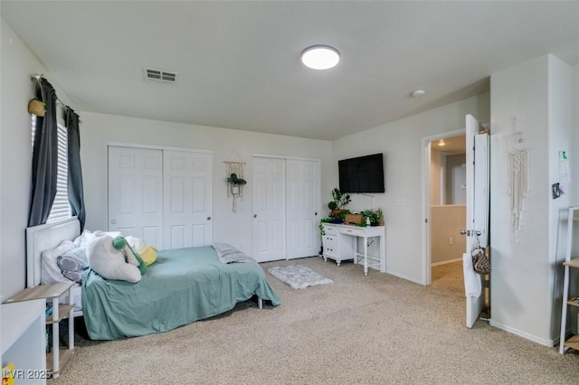 bedroom with light colored carpet and multiple closets