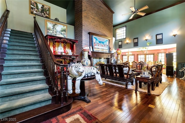 interior space featuring ornamental molding, wood-type flooring, ceiling fan with notable chandelier, and a high ceiling