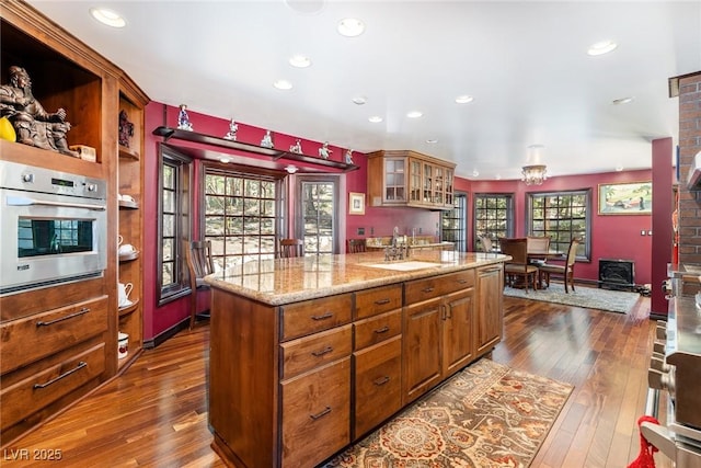 kitchen featuring light stone counters, dark hardwood / wood-style flooring, oven, and a healthy amount of sunlight