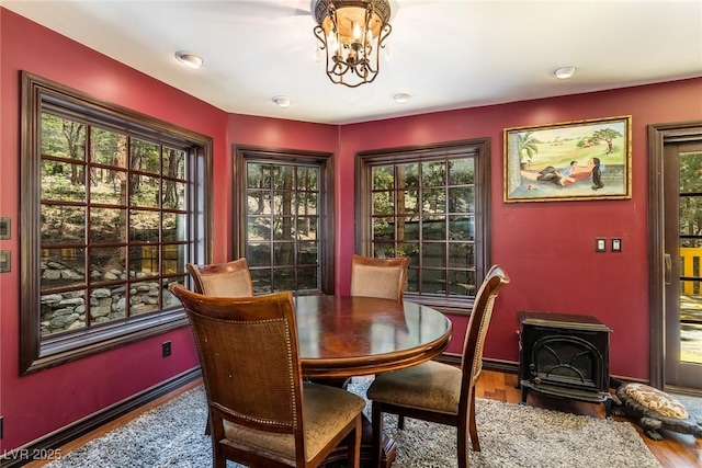 dining area featuring a chandelier, a wood stove, and wood-type flooring