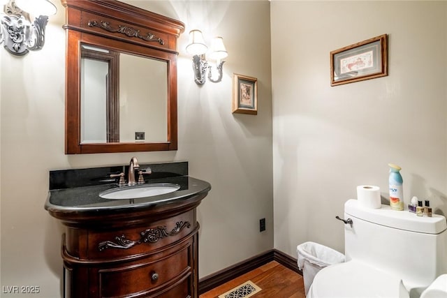 bathroom with hardwood / wood-style floors, toilet, and vanity