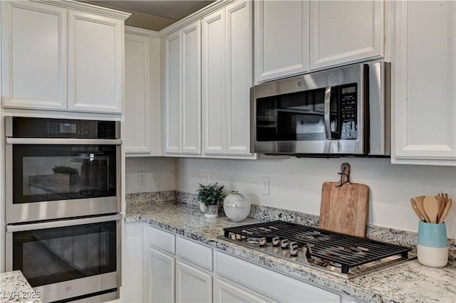 kitchen with light stone countertops, appliances with stainless steel finishes, and white cabinetry