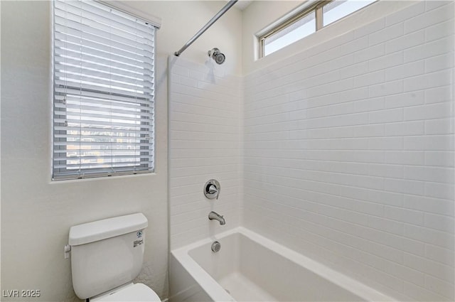 bathroom with tiled shower / bath combo and toilet