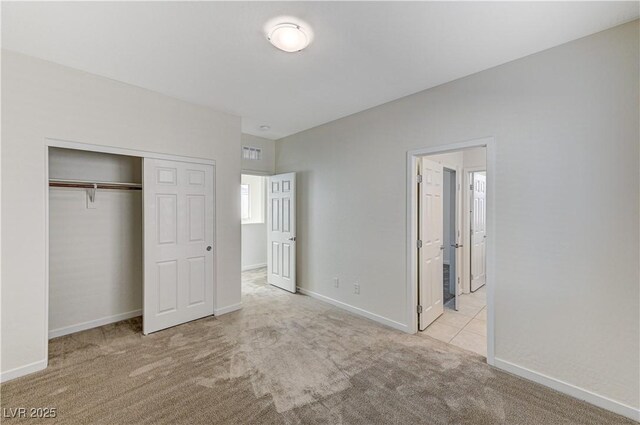 unfurnished bedroom with a closet and light colored carpet