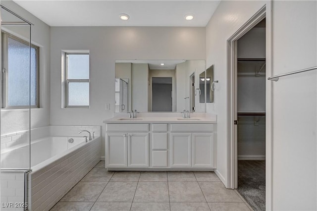 bathroom featuring tiled bath, vanity, and tile patterned flooring