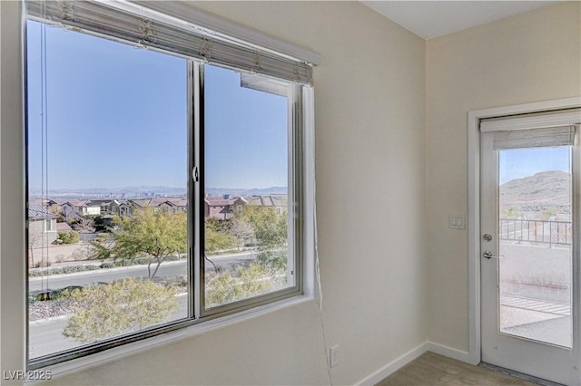 entryway with a mountain view, plenty of natural light, and carpet