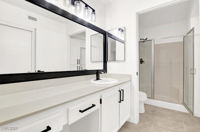 bathroom featuring toilet, vanity, tile patterned floors, and a shower with shower door