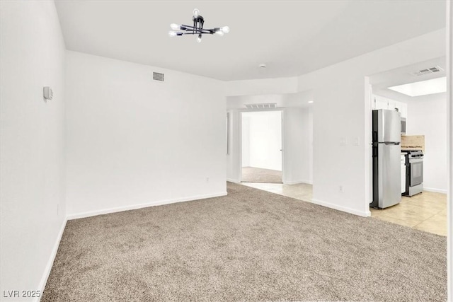 carpeted spare room with a chandelier