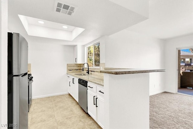 kitchen with white cabinetry, stainless steel appliances, sink, kitchen peninsula, and light stone counters