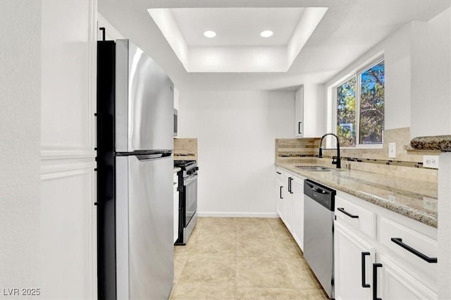 kitchen featuring sink, white cabinetry, a tray ceiling, and stainless steel appliances