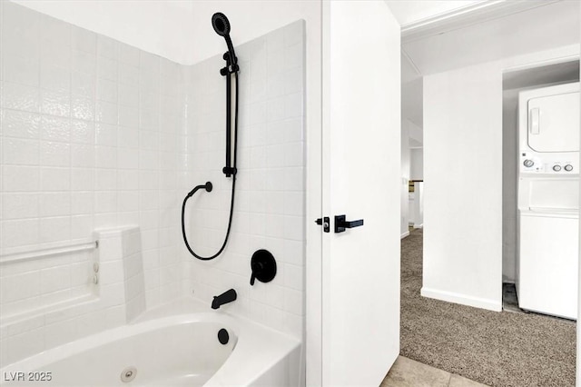 bathroom with tile patterned flooring, stacked washing maching and dryer, and shower / washtub combination