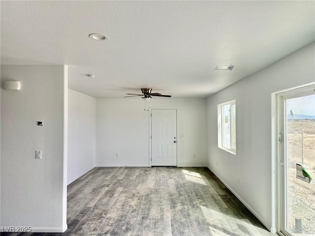spare room featuring baseboards, ceiling fan, and wood finished floors