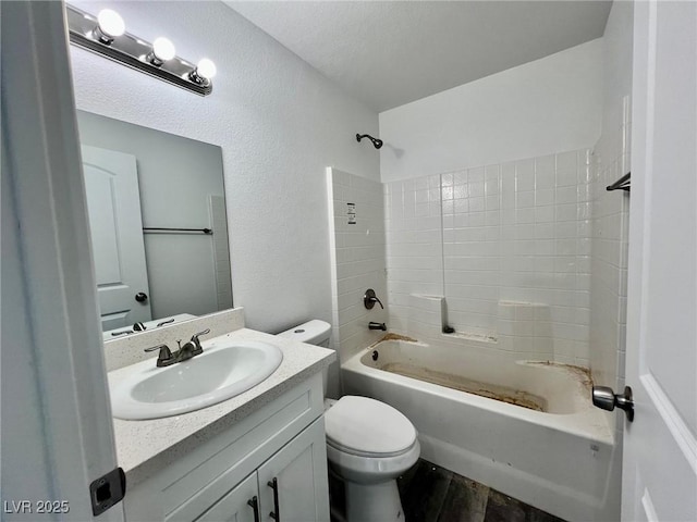 bathroom with vanity, a textured wall, wood finished floors, bathing tub / shower combination, and toilet