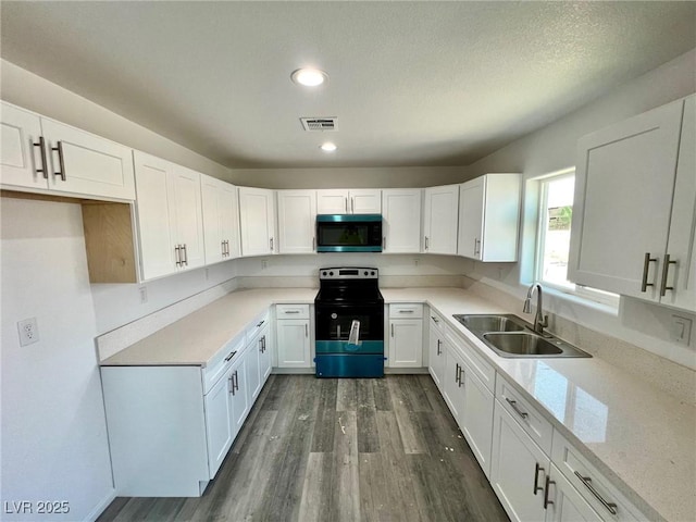 kitchen featuring dark wood-style floors, electric range oven, stainless steel microwave, white cabinetry, and a sink
