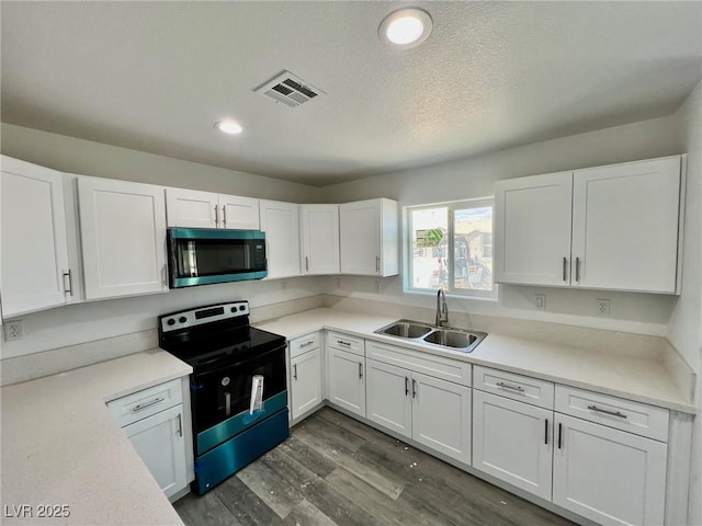 kitchen with electric range, visible vents, a sink, white cabinets, and stainless steel microwave
