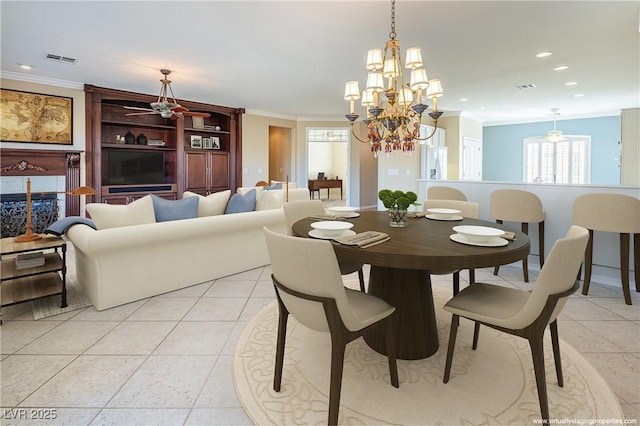 tiled dining space featuring a tile fireplace, ceiling fan with notable chandelier, and ornamental molding